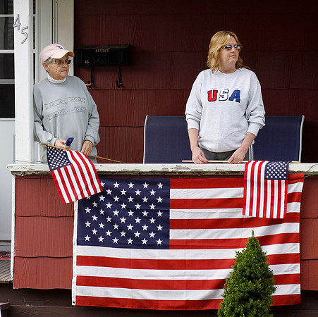 Pat Jones (left) and her daughter Tina Newton stand on the porch of Newton's house as Pittsfield and Berkshire, Mass. police and fire departments march down the road after a ceremony at the Pittsfield